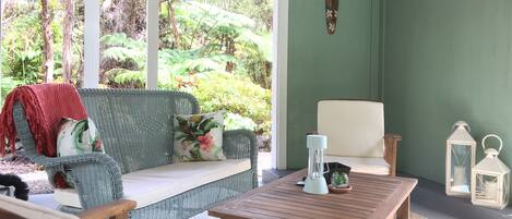 A cozy seating area with a wicker sofa, a wooden table, and a white chair.