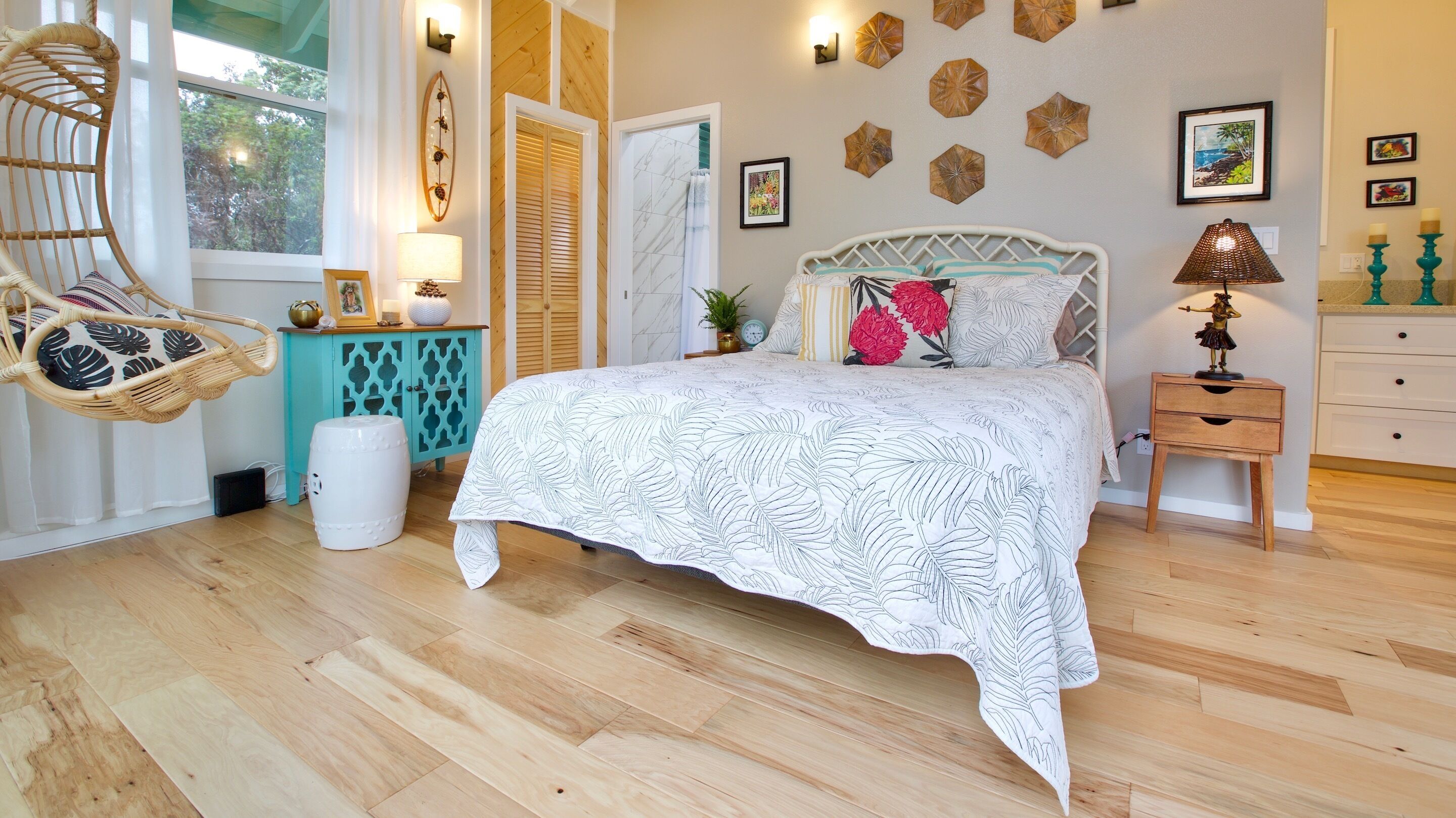 Un dormitorio con una cama, una silla de mimbre, una mesita y una mesilla de noche.