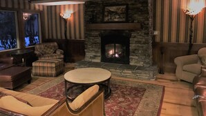 A cozy living room with a stone fireplace, striped wallpaper, and comfortable seating.