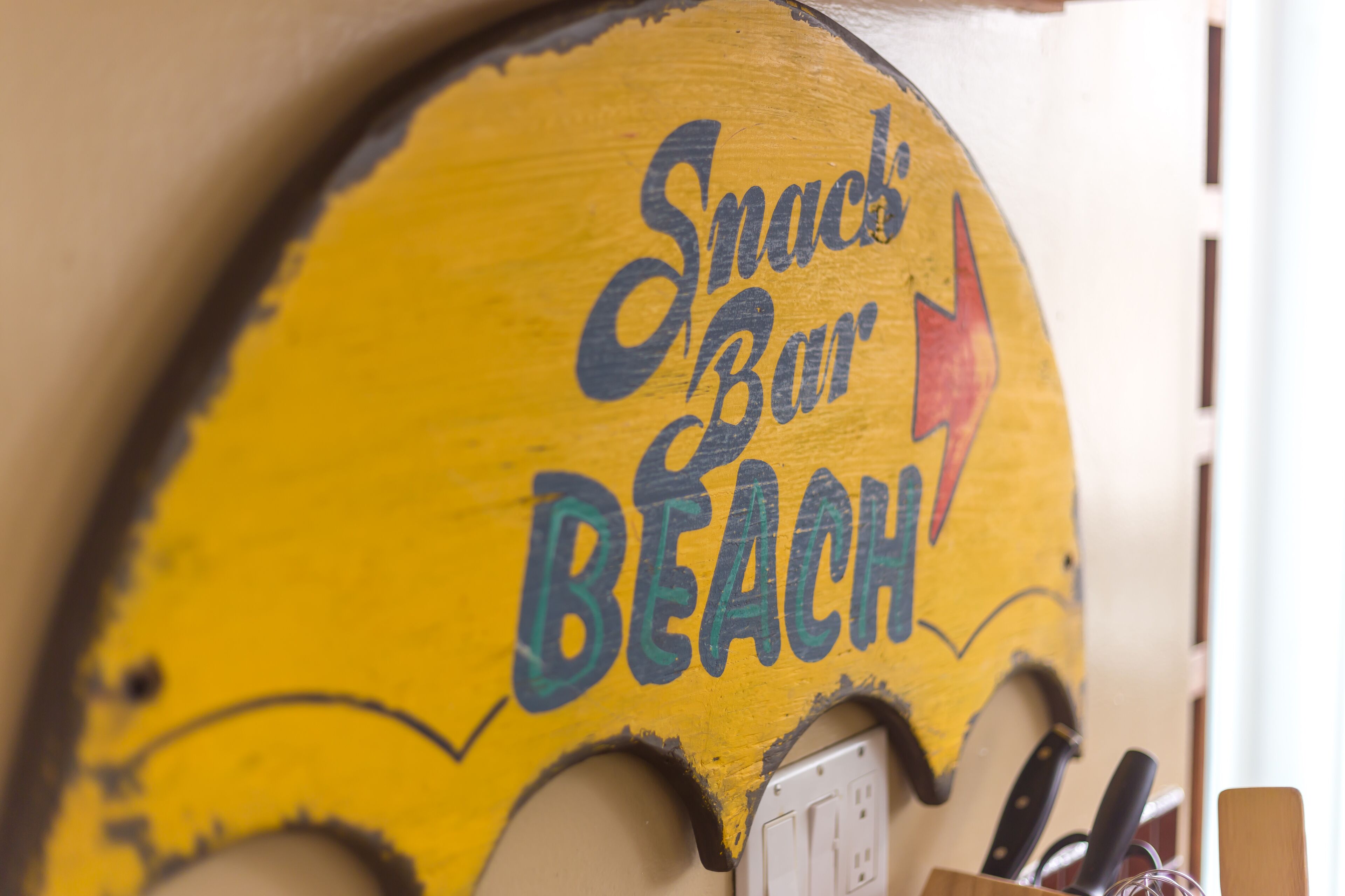 A yellow sign with the words "Snack Bar" and "Beach" written on it.