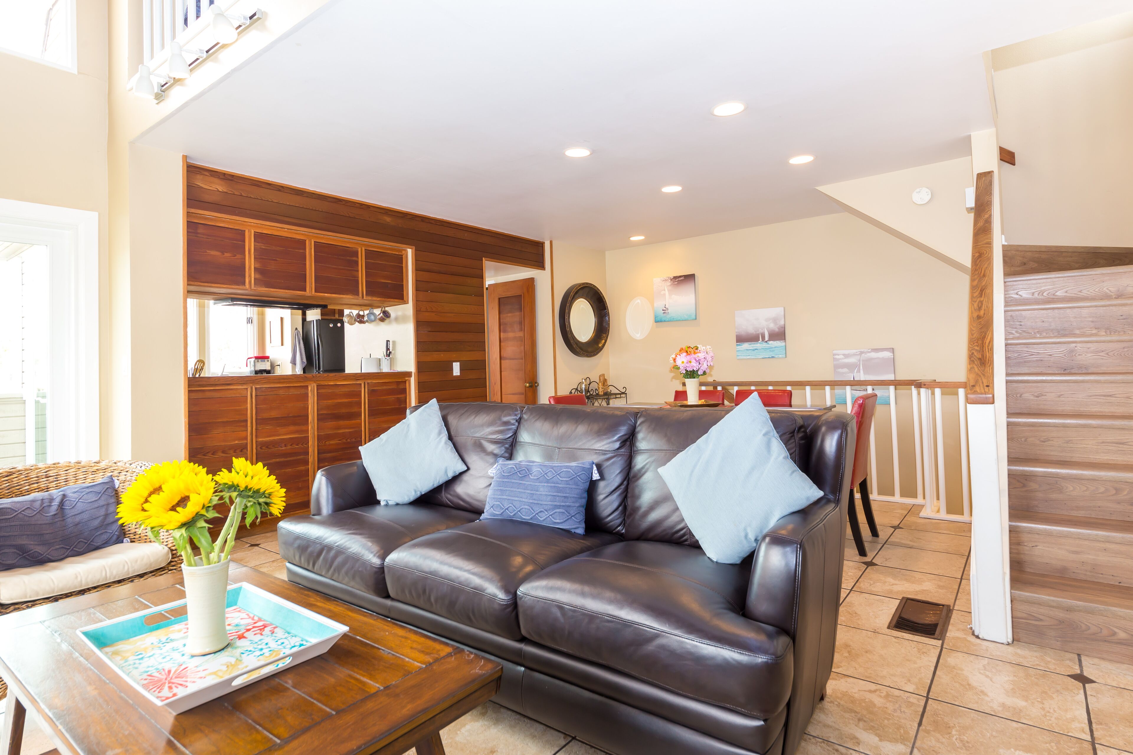A living room with a leather sofa, a coffee table, and a vase with flowers.