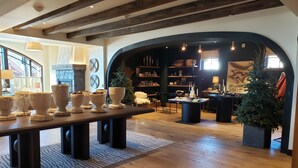 Une pièce spacieuse dotée d’un plancher en bois, d’une grande table ornée de vases décoratifs et d’un coin salon confortable avec une cheminée.