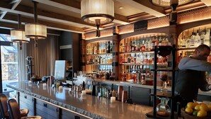 Un espace bar doté d’un comptoir en granit poli, de tabourets de bar et d’une variété de bouteilles d’alcool.