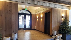 Un hall d’entrée au plancher de bois, avec un escalier en colimaçon menant à une porte marquée « SORTIE ».