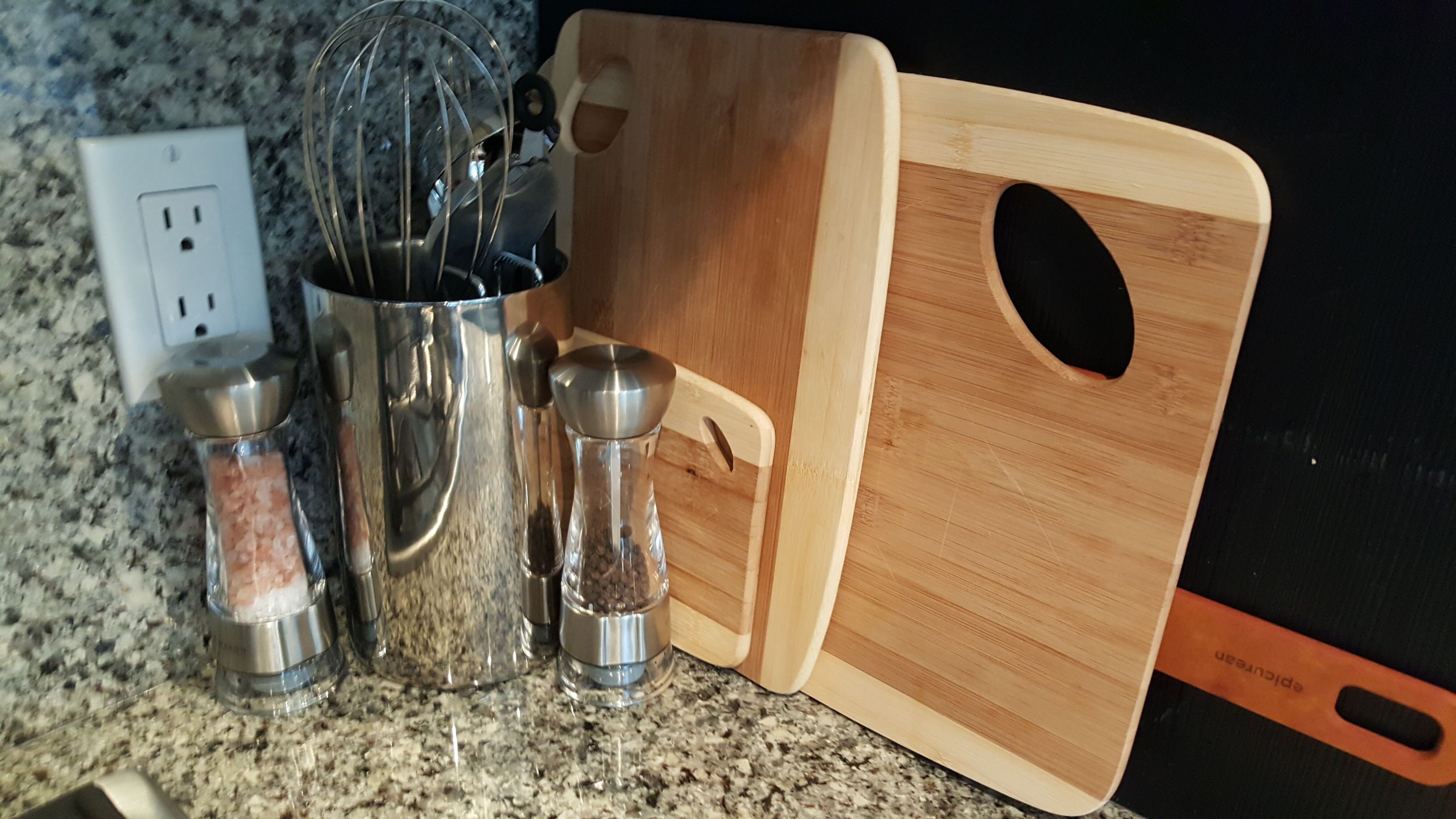 A kitchen counter with a mixing bowl, salt shakers, a wooden cutting board, and a blender.
