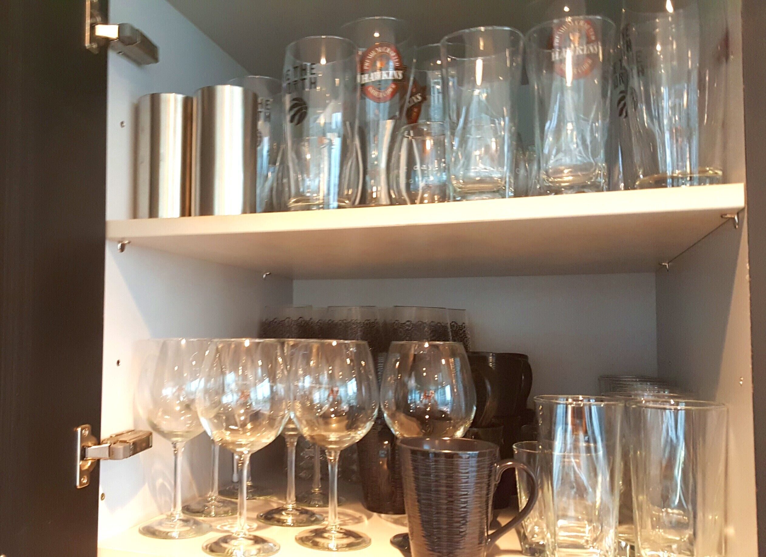 Una estantería con distintos vasos, incluyendo copas de vino y vasos de trago.