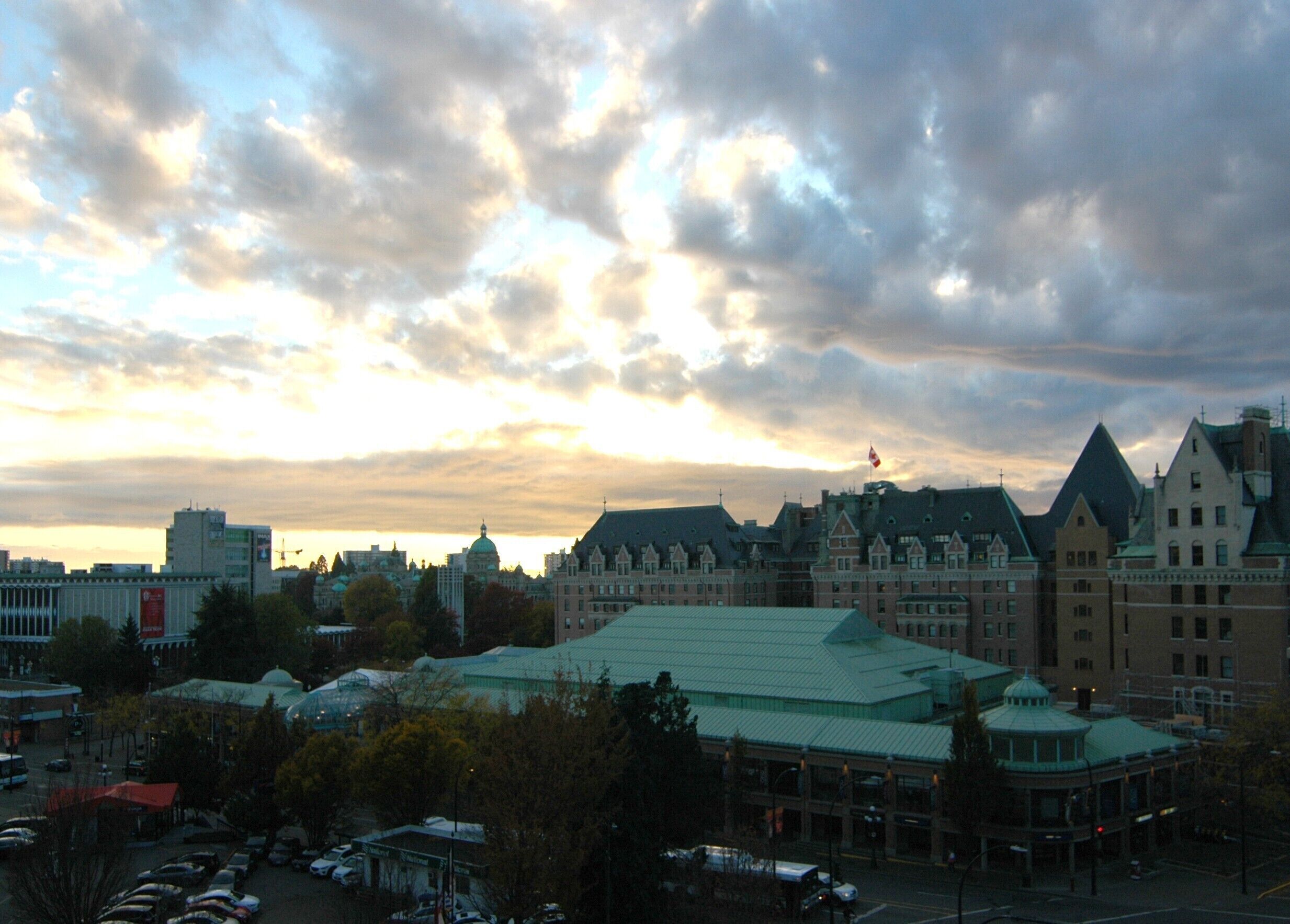 A historic building with a green roof, surrounded by trees and a parking lot.