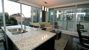 A modern kitchen with granite countertops, a built-in sink, and a large window overlooking a cityscape. - The Falls: The Waterfalls Hotel: Luxury Oasis at the Falls in Victoria, BC (Victoria)