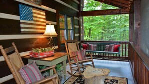 A cozy porch with wooden furniture, a Coca-Cola crate, and a decorative American flag.