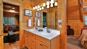 A wooden cabin bathroom with two sinks, a large mirror, and a wooden vanity.