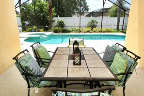 Um pátio com mesa e cadeiras, um candeeiro e vista para uma piscina.