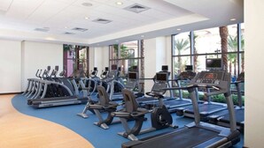 A gym with multiple treadmills and exercise bikes, large windows, and a curved wooden floor. - Minutes away from all the fun at Disney Resorts!  Everything you need and want! (Orlando)