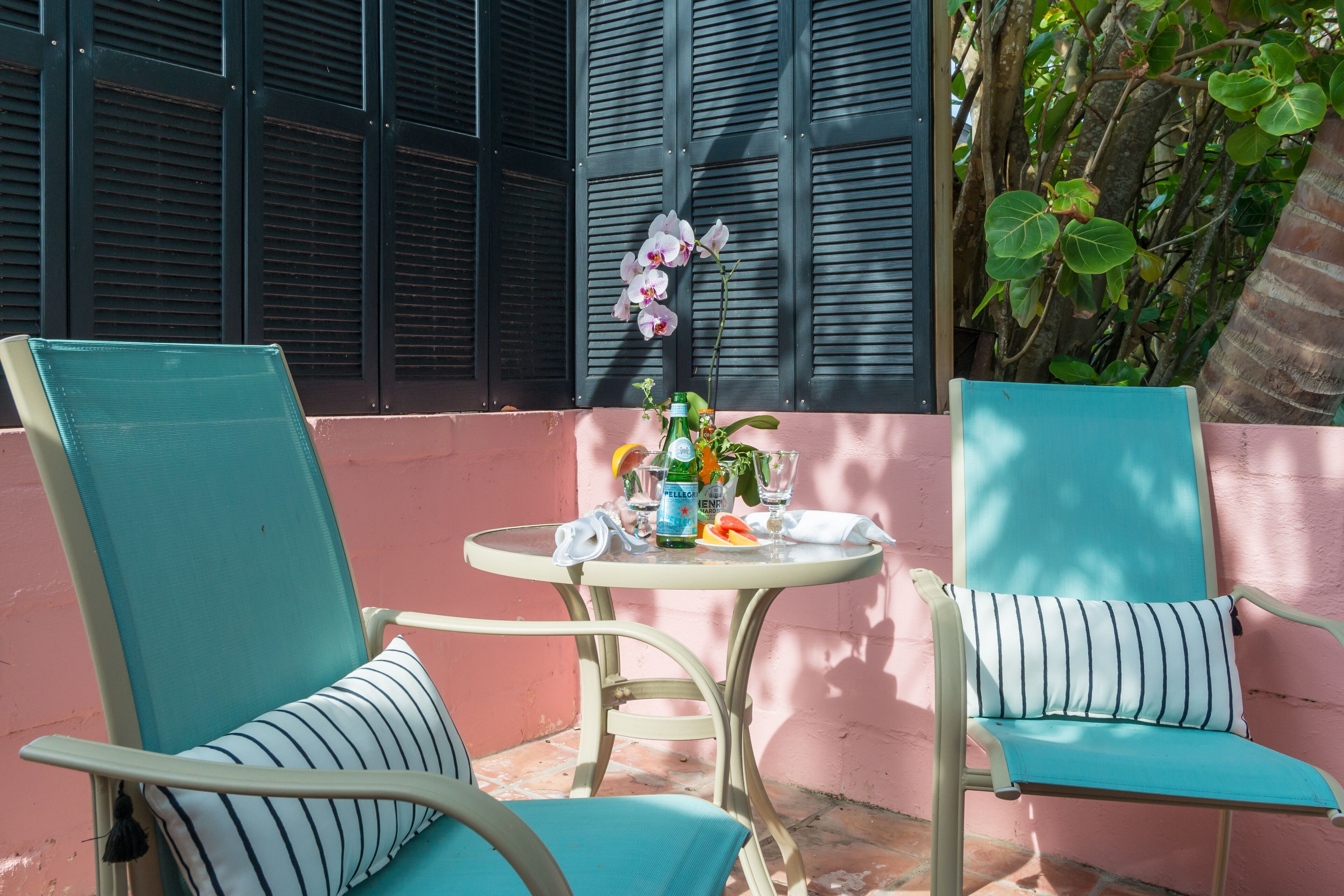 Een terras met twee stoelen, een tafel en een decoratieve orchidee.