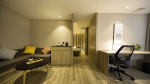 Une chambre d’hôtel moderne équipée d’un canapé, d’une petite table, d’un bureau et d’une chaise.