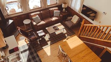 A cozy living room with a wooden dining table, a sofa, and a fireplace.
