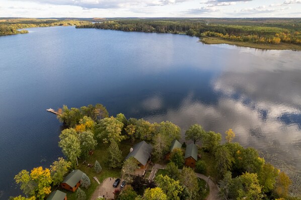 A lakeside property with cabins, a dock, and surrounding forest.