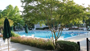 A pool area with lounge chairs and umbrellas, surrounded by trees and flowers. - Coastal Greens Getaway-3 BR Golf Villa.  Plan now for a fall getaway! (Ocean View)