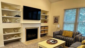 A living room with a fireplace, a television, and a sofa. - Coastal Greens Getaway-3 BR Golf Villa.  Plan now for a fall getaway! (Ocean View)
