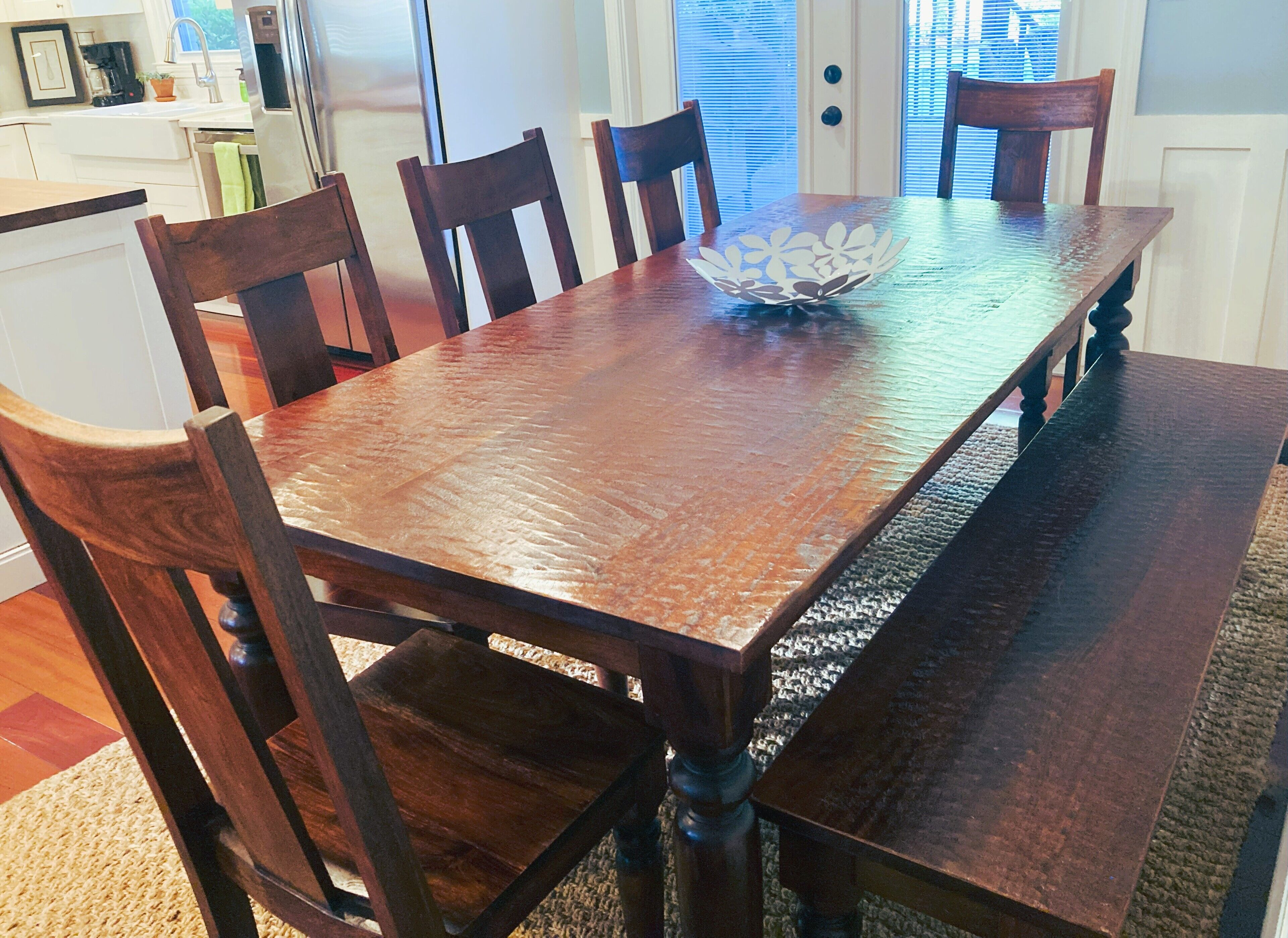 Una mesa de comedor de madera con un centro de mesa en un bol, rodeada de sillas de madera.