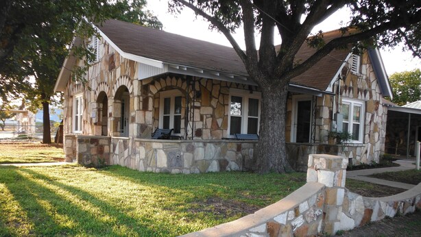 A stone house with a porch and a large tree in front. - Kaiser House in the heart of the Texas Hill Country (Harper)