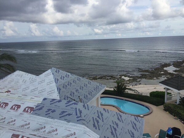 A pool area with a view of the ocean and beach.