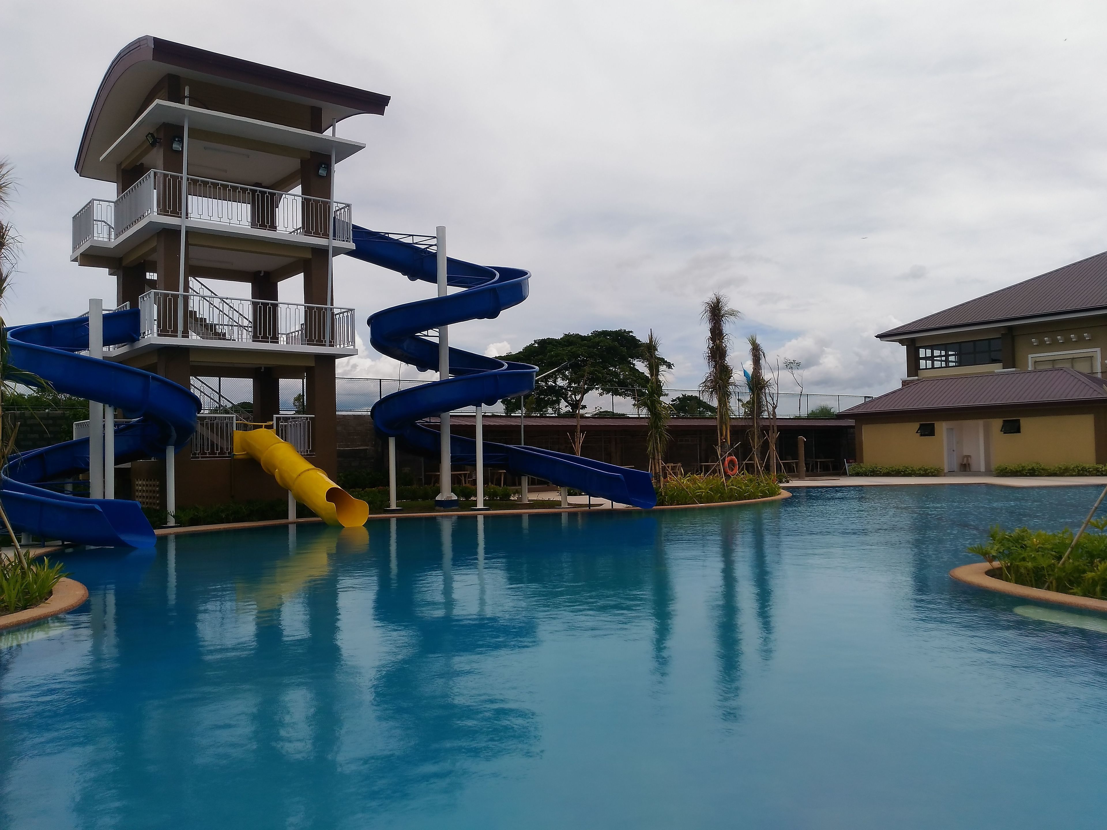 A swimming pool with multiple water slides, a multi-story building with balconies, and a clear sky.