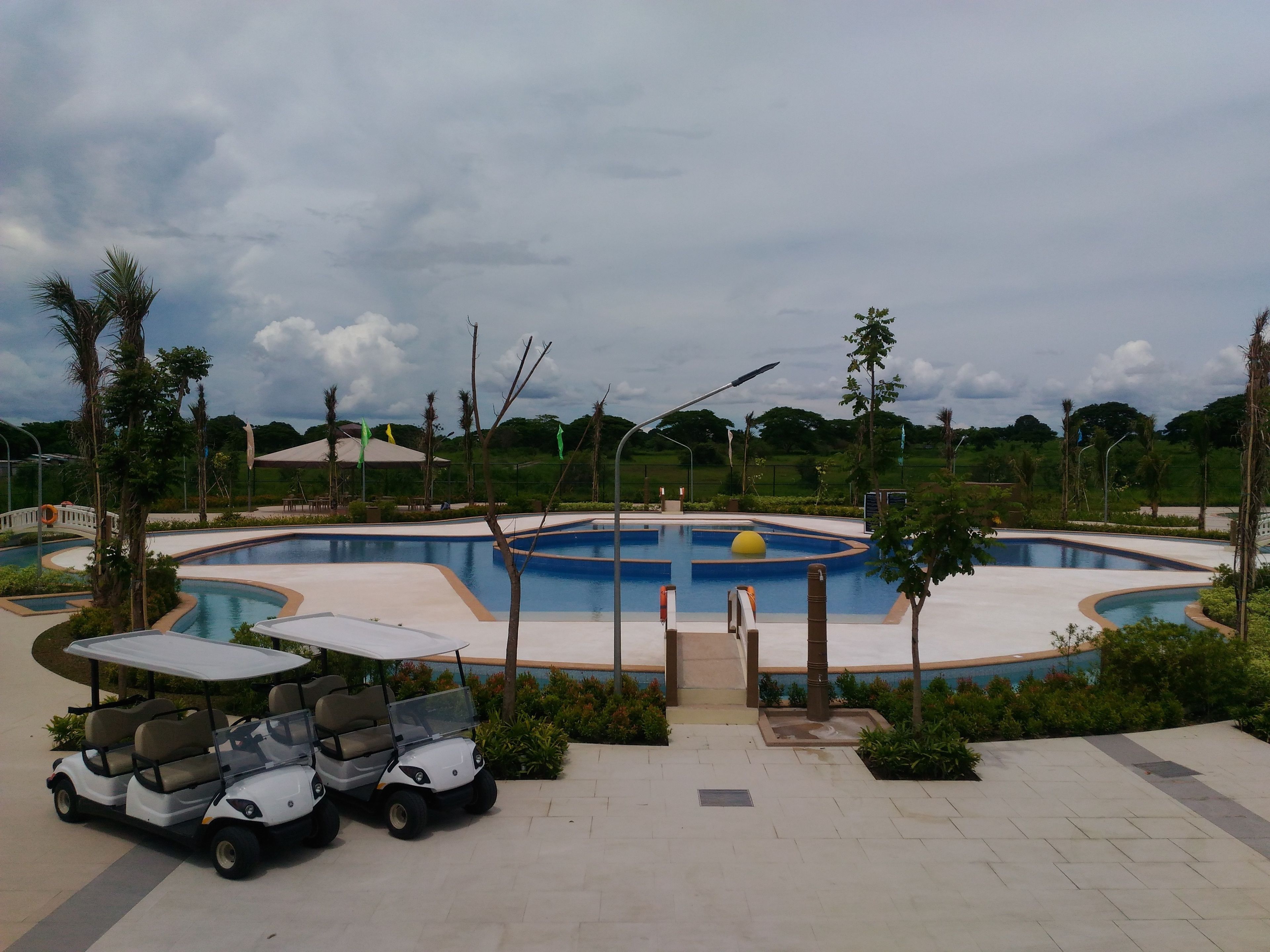 Un espace piscine comprenant une piscine circulaire, un véhicule de golf et un espace de détente abrité.