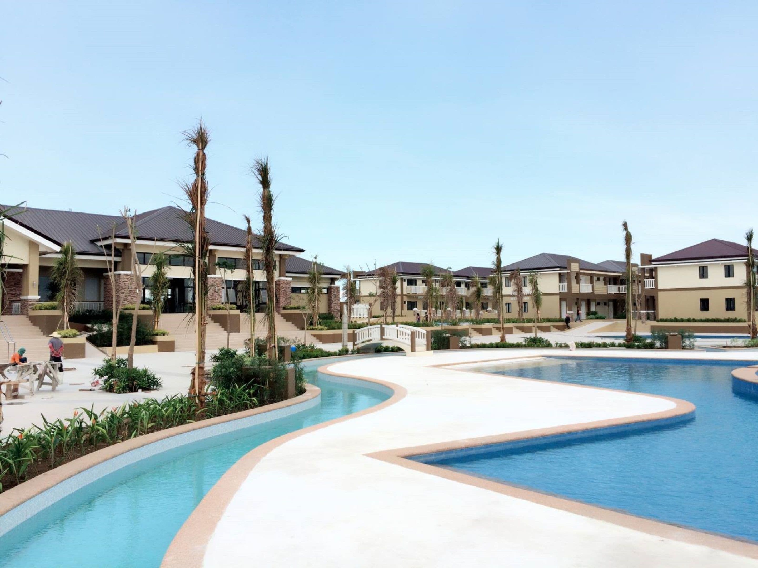 Un resort con una piscina grande, varias edificaciones y palmeras.
