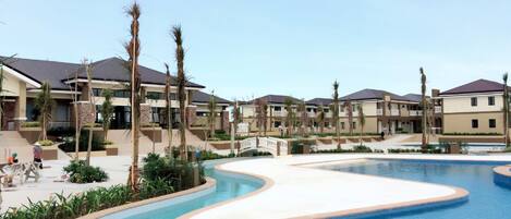 Un resort con una piscina grande, varias edificaciones y palmeras.