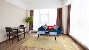 A modern living room with a sofa, a coffee table, a dining table with chairs, and a potted plant. - ibis Kunshan Changjiang Rd Hotel (Suzhou)