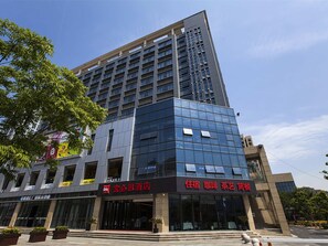 Un hôtel moderne, avec une façade en verre, de nombreux étages et une entrée imposante agrémentée d’une enseigne.