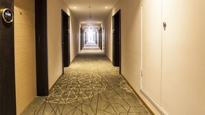 A hotel hallway with a geometric patterned carpet, a sign indicating room number 1106, and doors on both sides. - ibis Kunshan Changjiang Rd Hotel (Suzhou)
