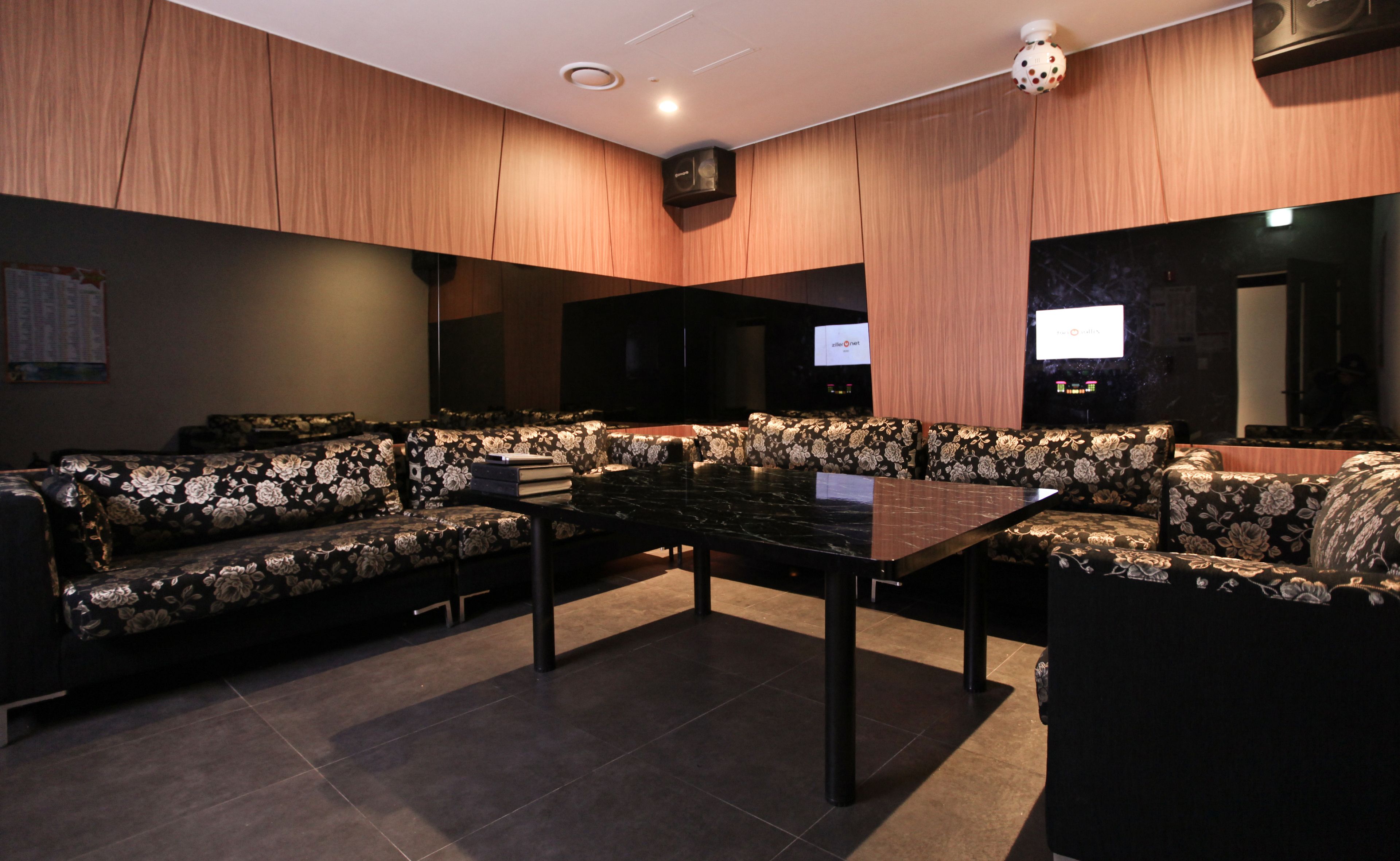 A modern lounge with a sectional sofa, a marble table, and a flat-screen TV mounted on the wall.