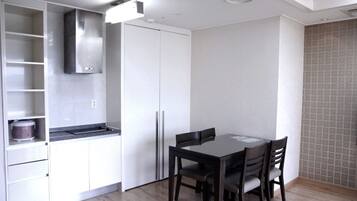 Una cocina compacta con estufa integrada, un refrigerador blanco y una mesa de comedor con sillas.
