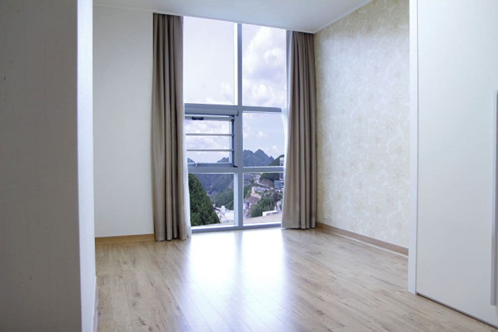 Una habitación con un ventanal grande, suelo de madera y pared lisa.