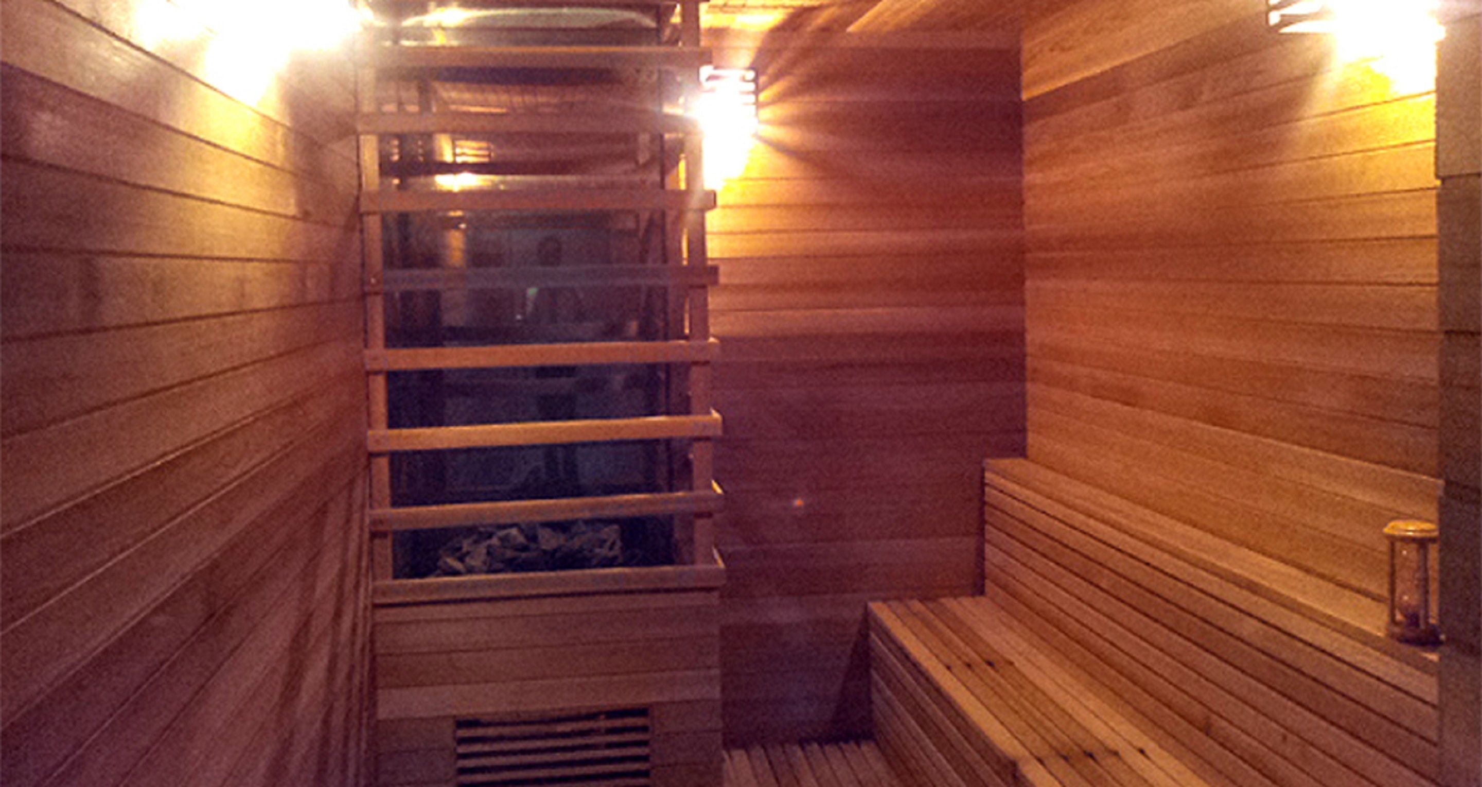 A sauna with wooden benches and a ladder leading to a higher level.