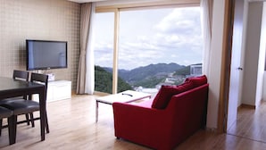 A modern hotel room with a dining area, a red sofa, and a large window offering a mountain view. - High Castle Resort (Jeongseon)