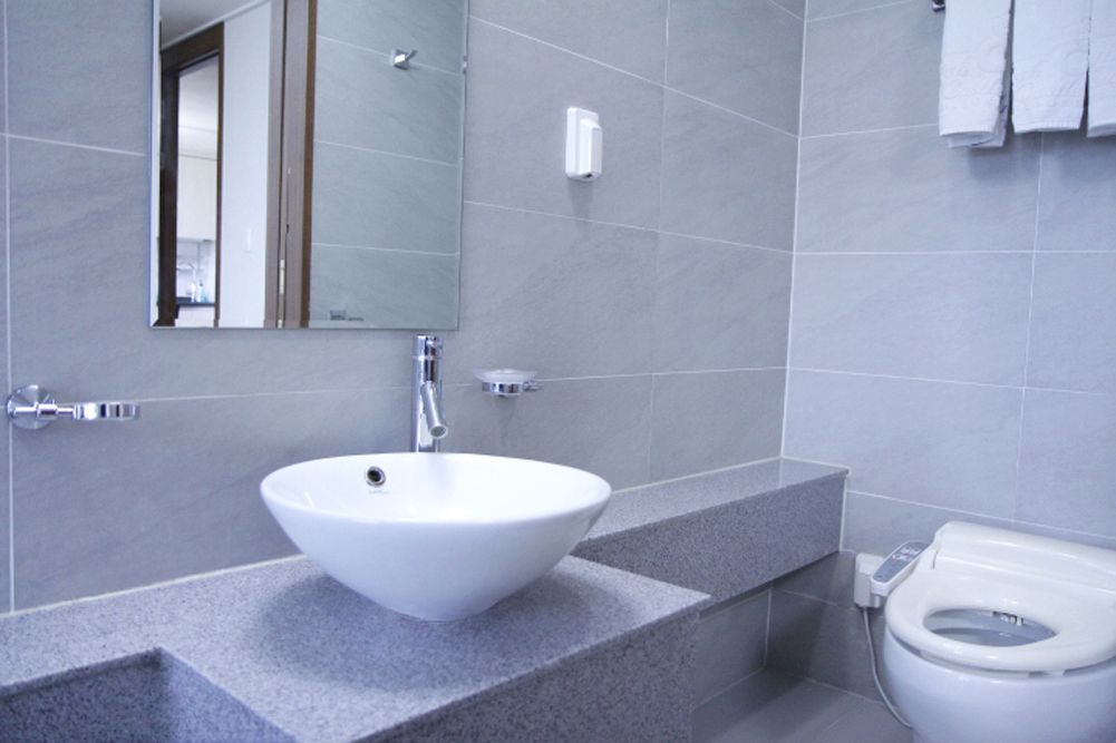 A modern bathroom with a white sink, a mirror, and a toilet.