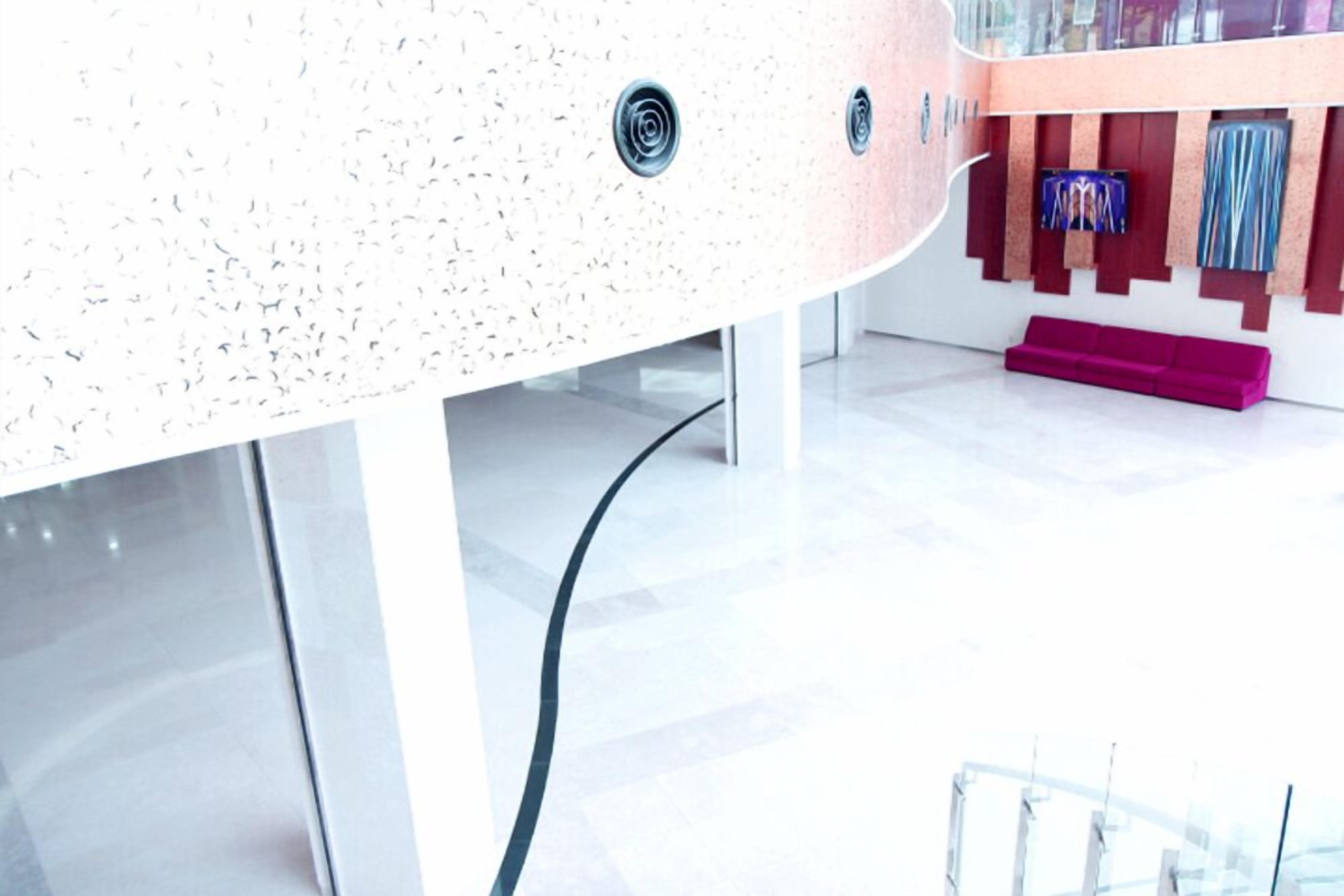 Un interior moderno con techo curvo, un sofá rosa y un televisor montado en la pared.