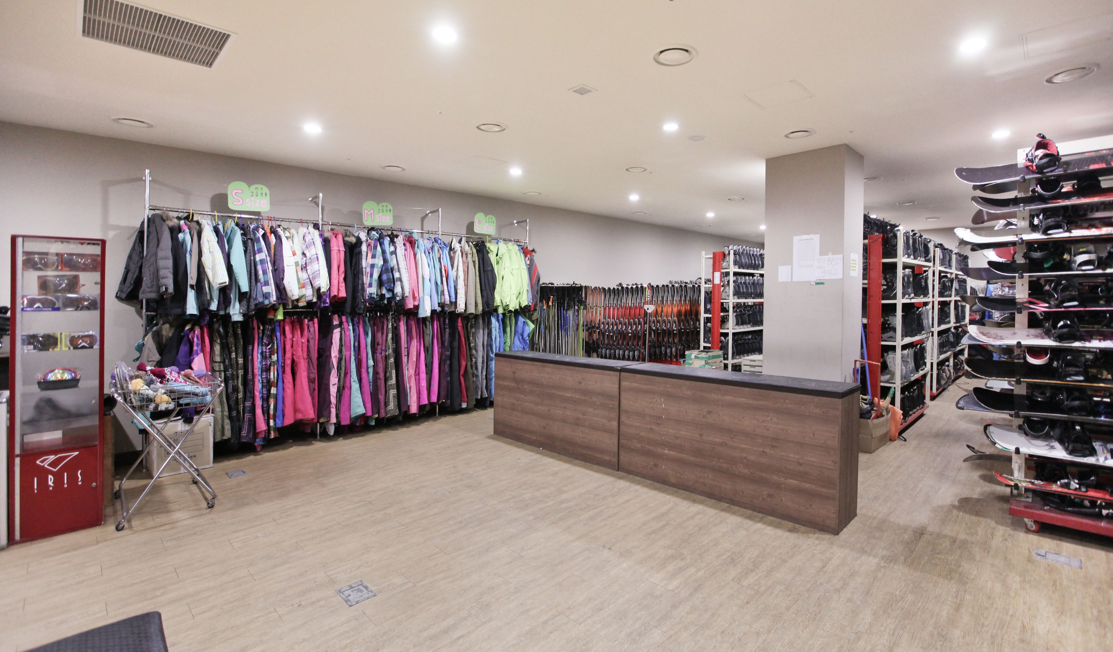 Una tienda minorista con percheros de ropa, un mostrador y estantes llenos de zapatos.