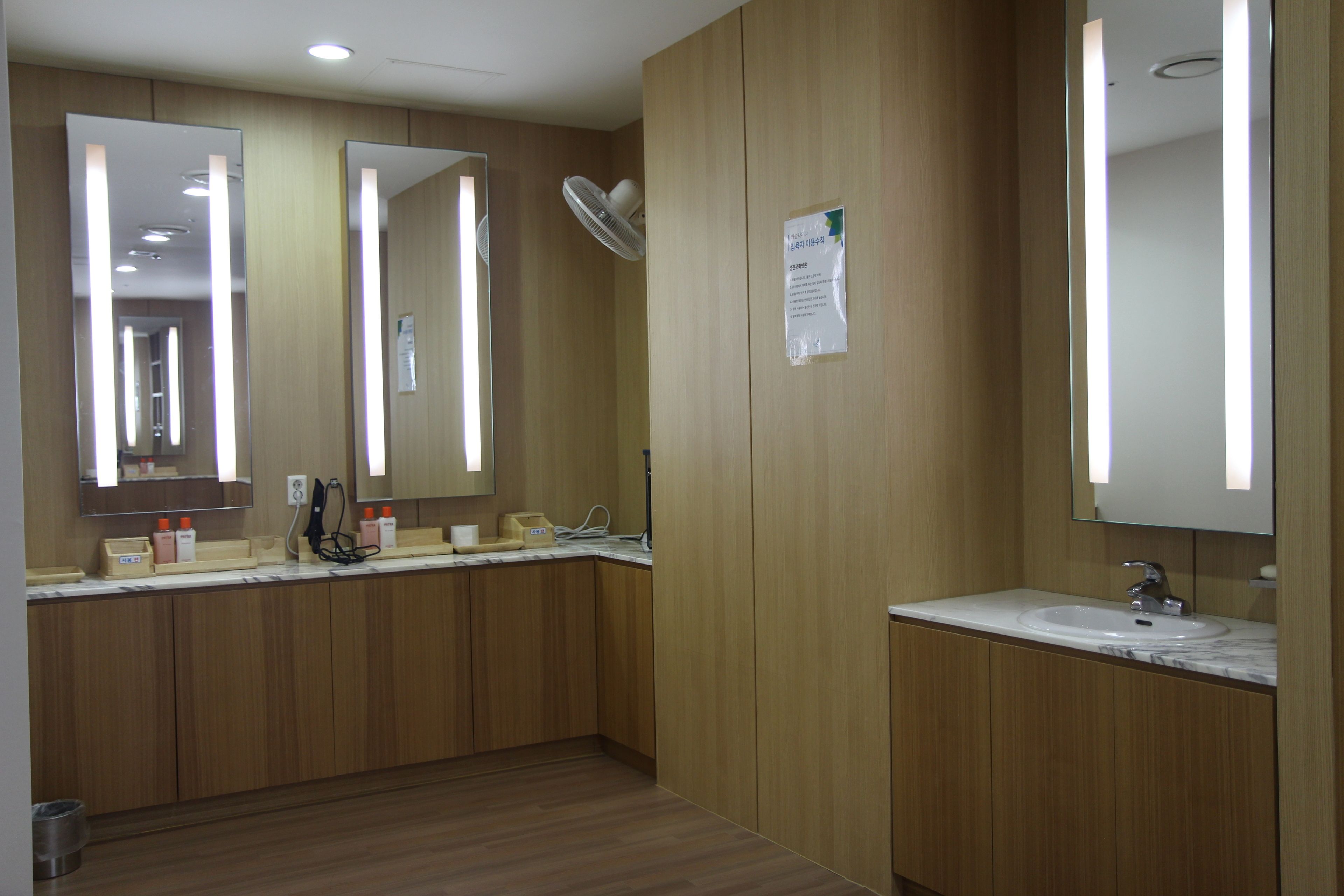 Un baño moderno con paneles de madera, encimera de mármol, un lavabo y un espejo.