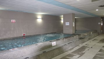 Swimmers can enjoy a refreshing dip in the rectangular pool surrounded by a tiled floor and steps leading up to the water's edge.
