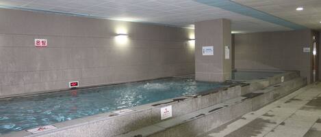 A swimming pool with multiple lanes, tiled walls, and a ceiling with recessed lighting.