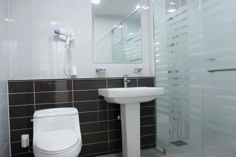 Ein modernes Badezimmer mit Toilette, Waschbecken auf Säule und Duschkabine aus Glas.