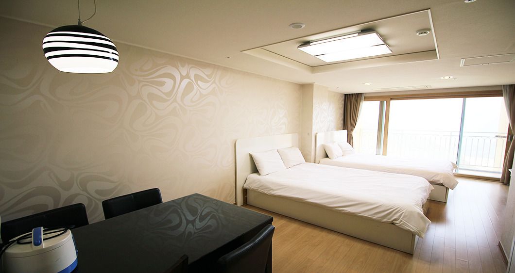 A hotel room with a bed, a desk, and a chair. There is a window with curtains and a view of the outside.