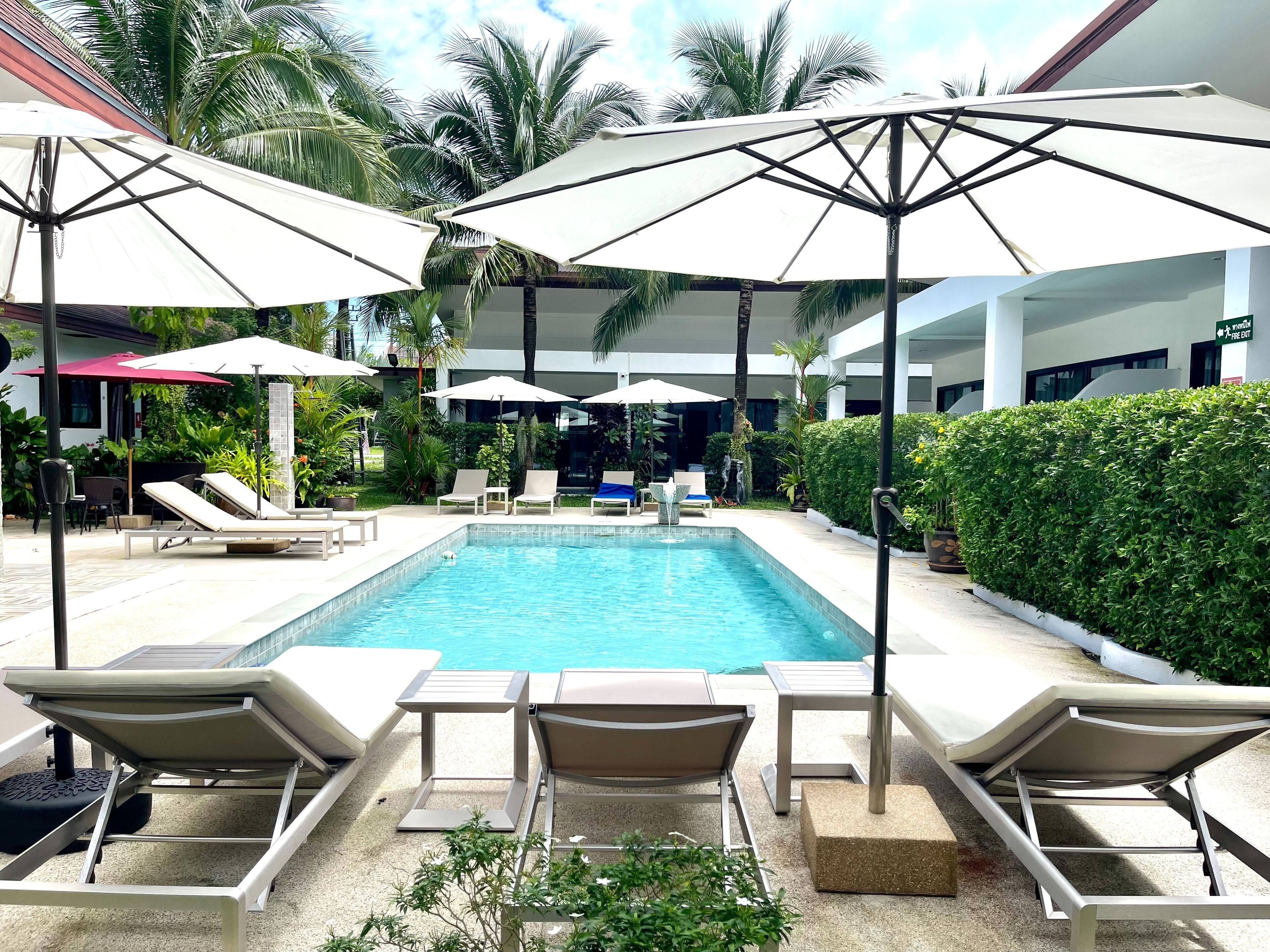 A poolside area with lounge chairs, umbrellas, and a clear blue pool.