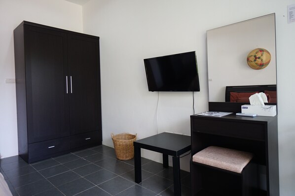 A room with a large wardrobe, a television mounted on the wall, a small table, and a bed with a headboard. - Lotus Bleu Resort & Restaurant (Rawai)
