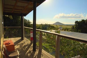 A balcony with a view of a mountain, a fire extinguisher, and a table with chairs. - The Beehive Fiji (Rakiraki)