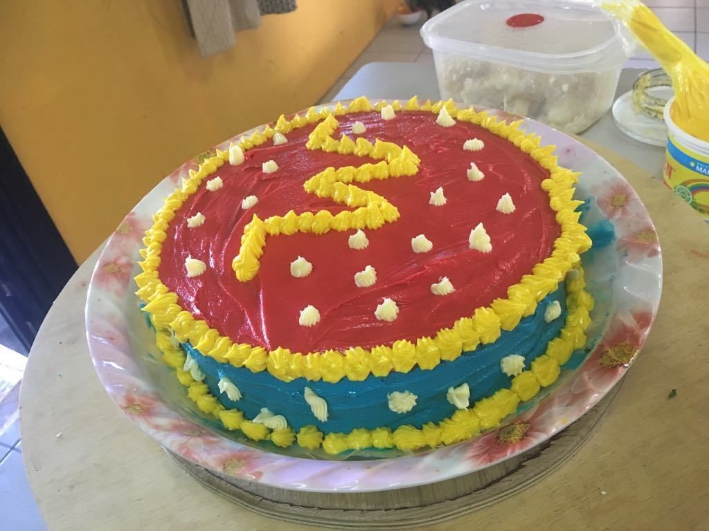 A cake with yellow and red frosting on a floral plate.