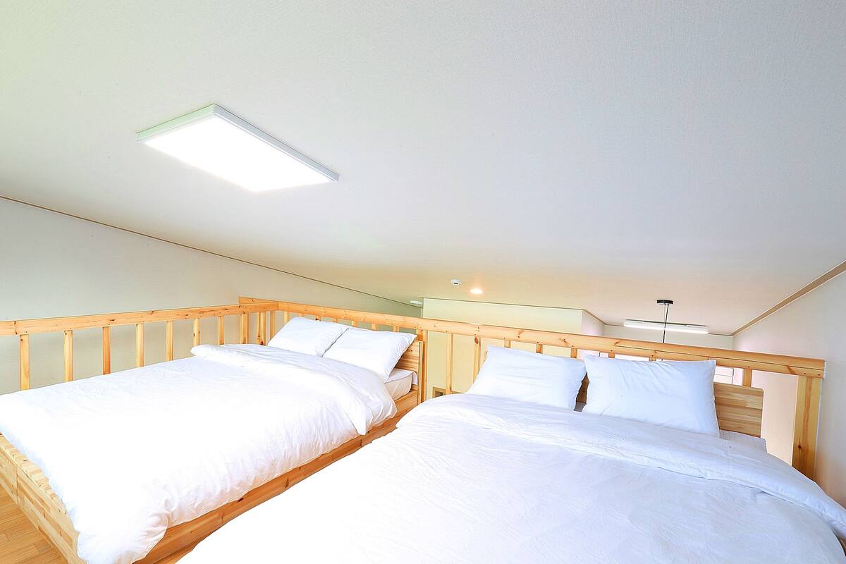 A bedroom with two wooden beds, white bedding, and a ceiling light fixture.